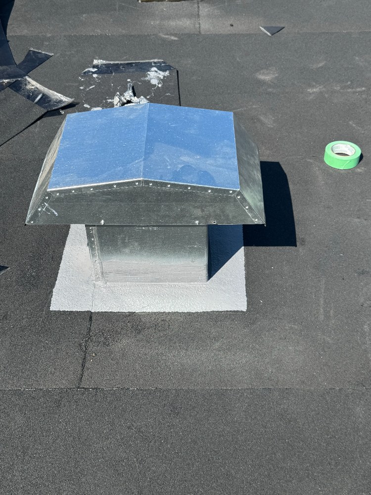 Fabricated sheet metal vent cap set on a flashed roof curb